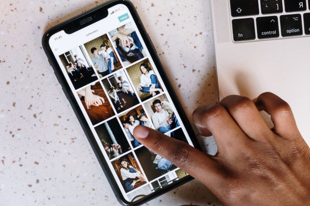 Close-up of a person browsing social media on a smartphone next to a laptop.